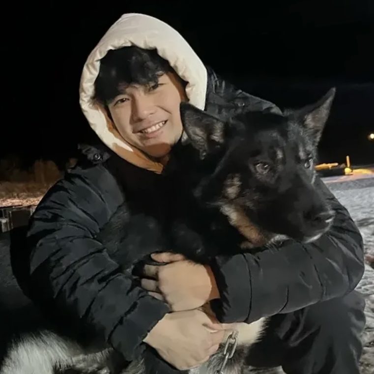 Ryan Li holding a dog outside in winter